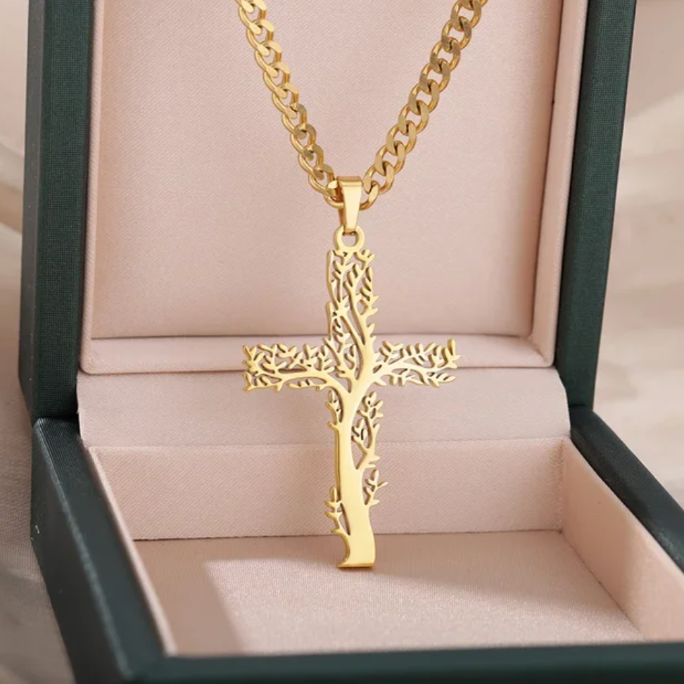 A gold-colored cross pendant cuban chain necklace in a presentation box with a soft pink lining.