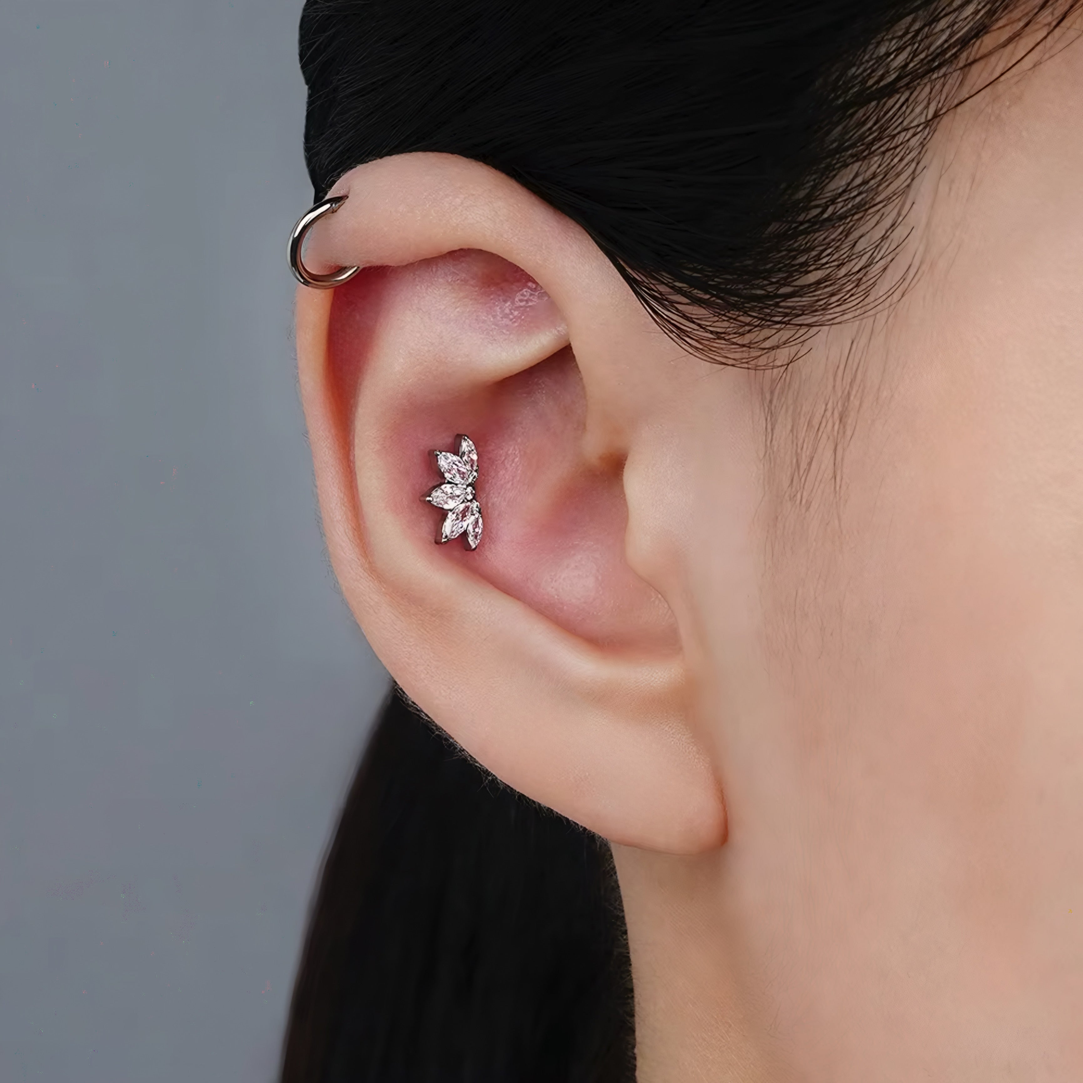 Close-up of an ear with a diamond earring against a neutral background