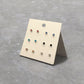 Set of small earrings on a display card against a gray background