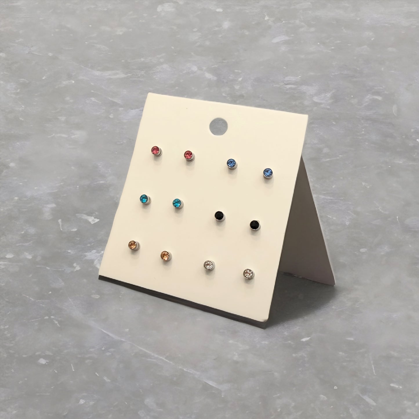 Set of small earrings on a display card against a gray background