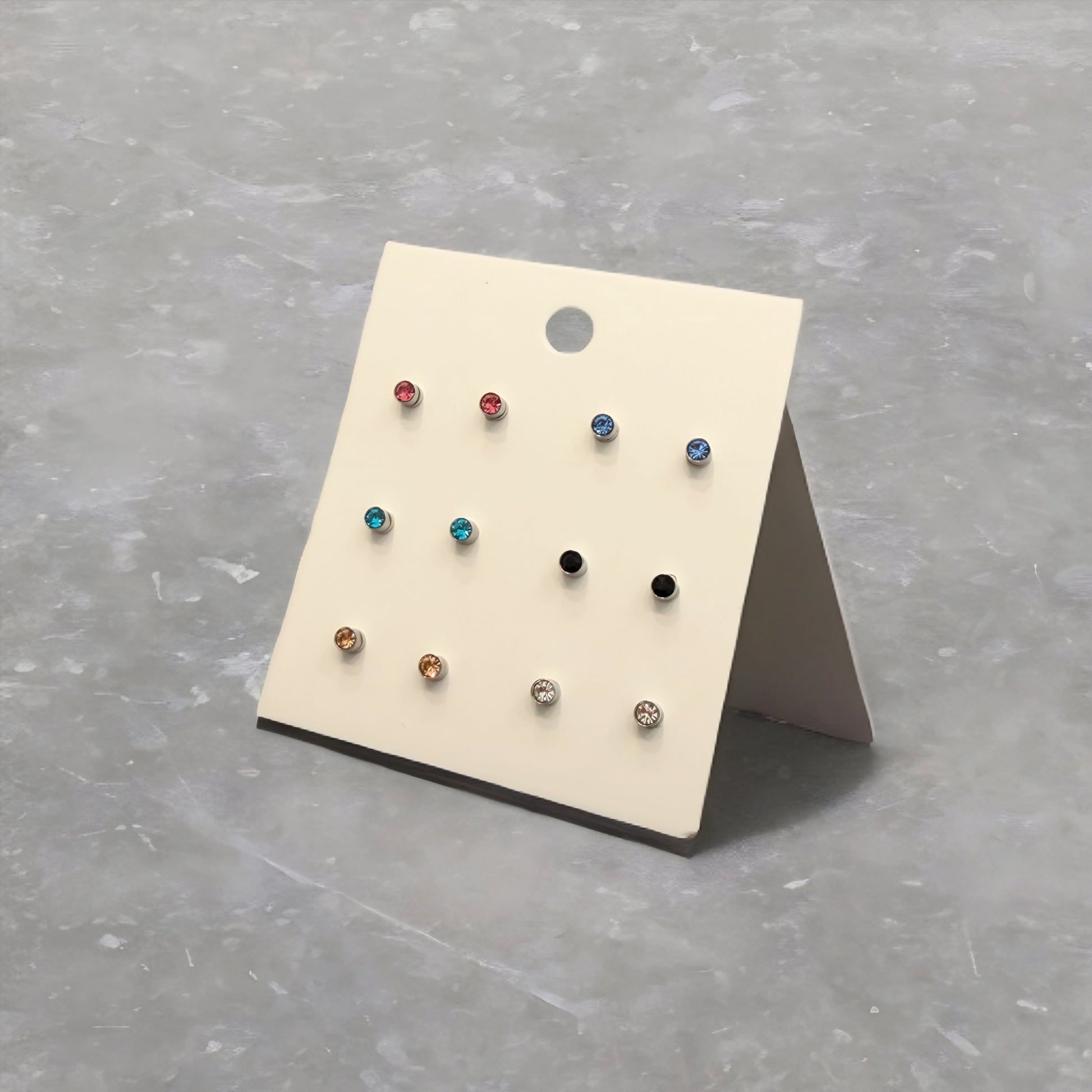 Set of small earrings on a display card against a gray background