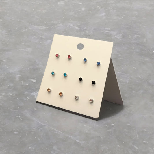 Set of small earrings on a display card against a gray background