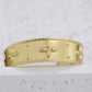 Gold bracelet with floral patterns on a light gray background