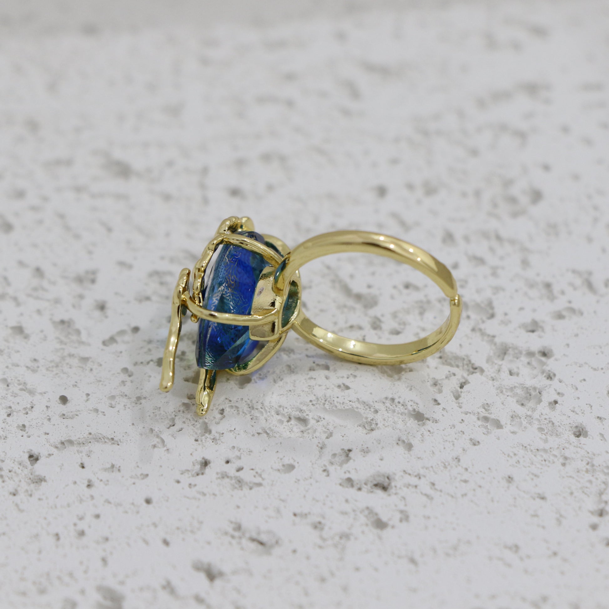 Gold ring with a blue gemstone on a textured gray surface