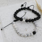 Two beaded bracelets, one black and one with a mix of black and white beads, on a textured surface.