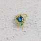 Gold ring with a blue and green gemstone on a textured gray background