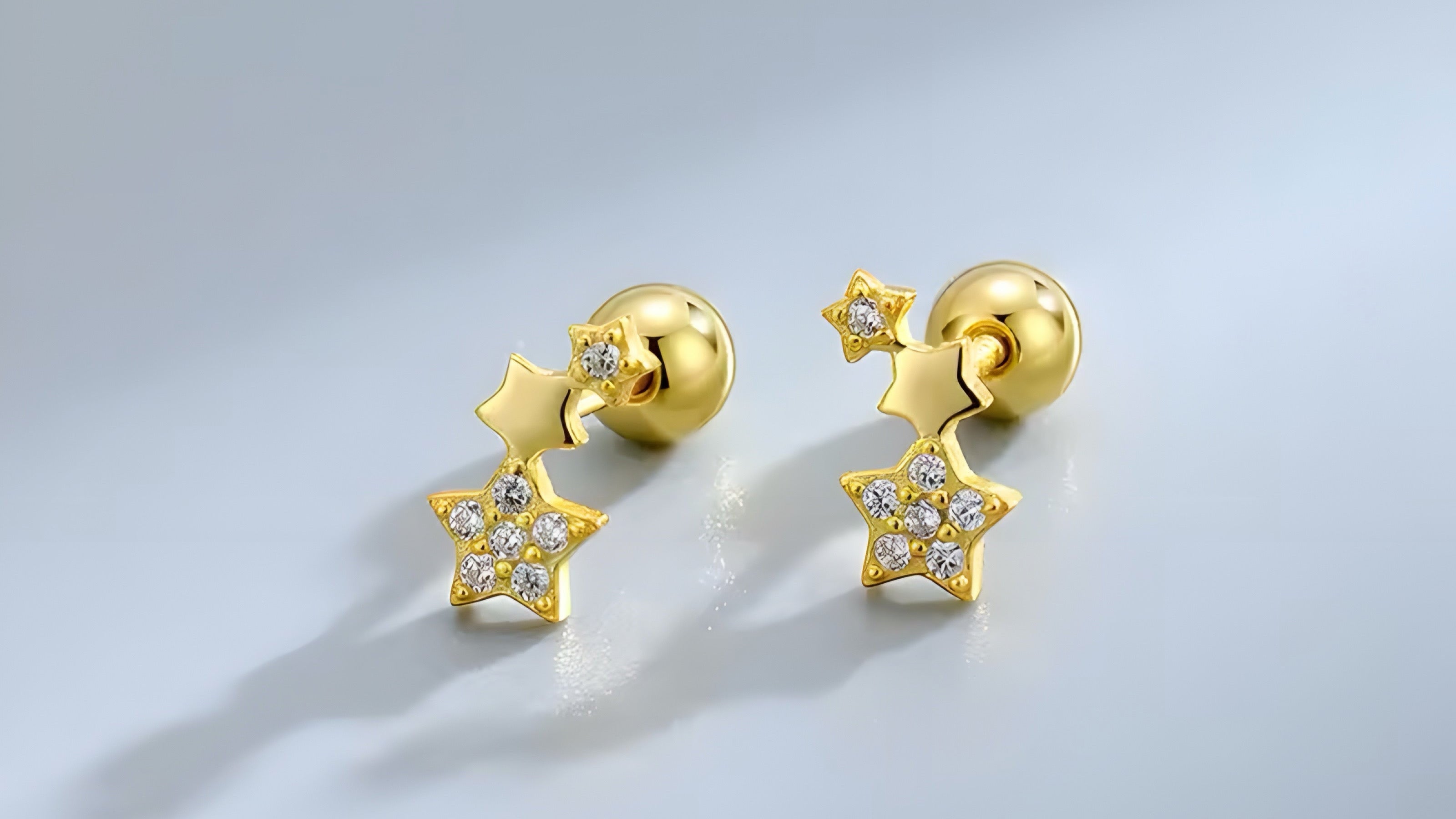 Gold star-shaped earrings with embedded stones on a light gray background
