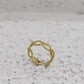 Gold ring with a subtle design on a gray surface with infinity sign