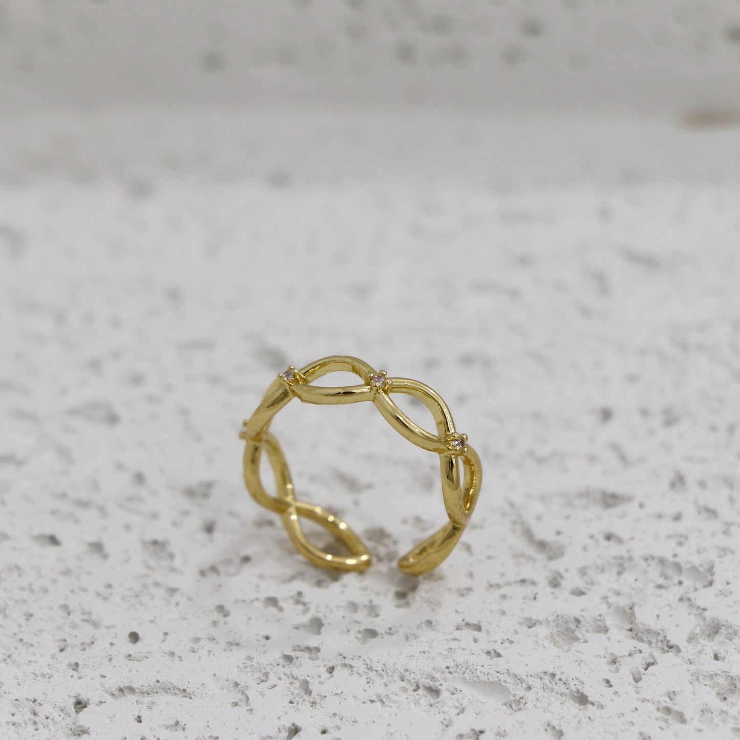 Gold ring with a subtle design on a gray surface with infinity sign