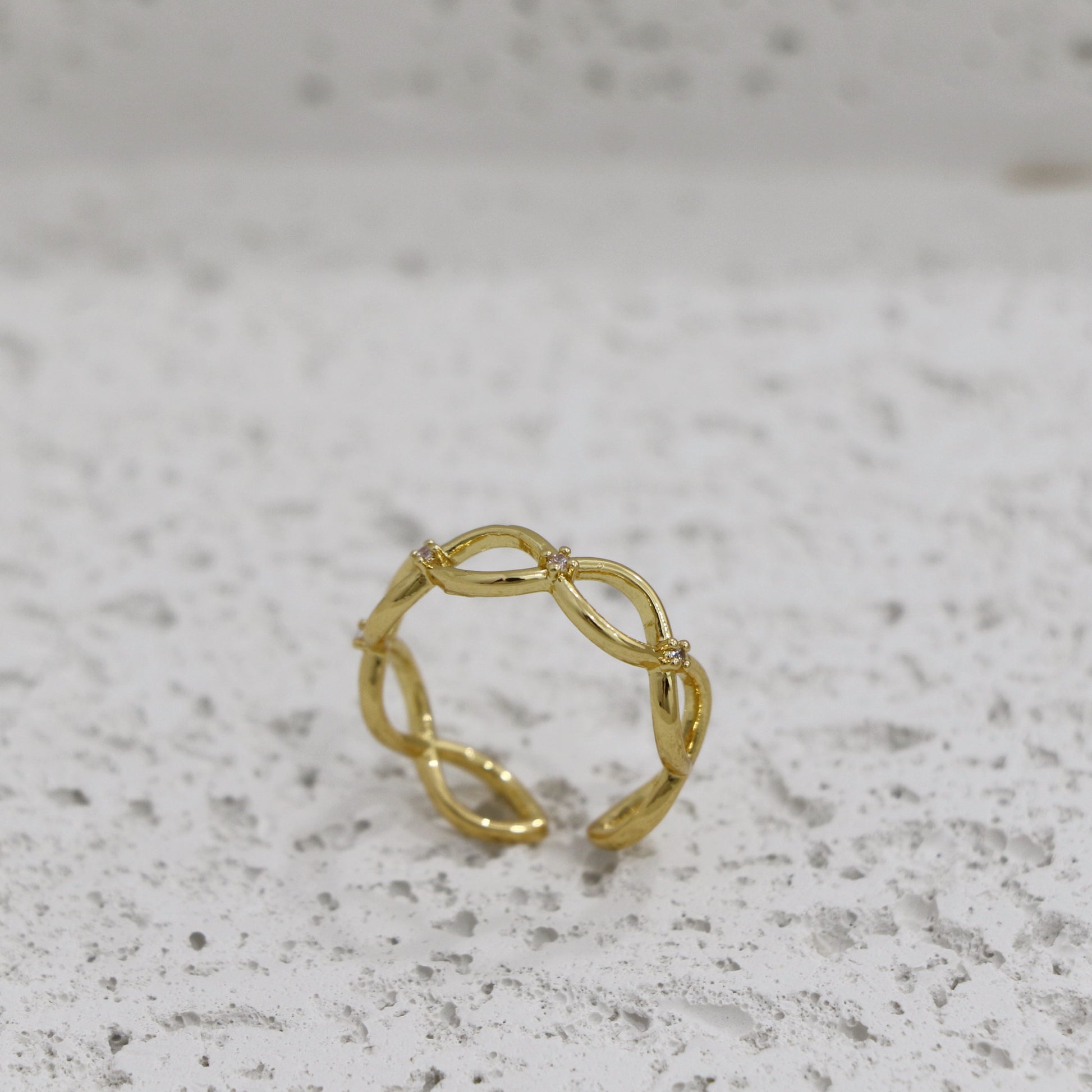 Gold ring with a subtle design on a gray surface with infinity sign