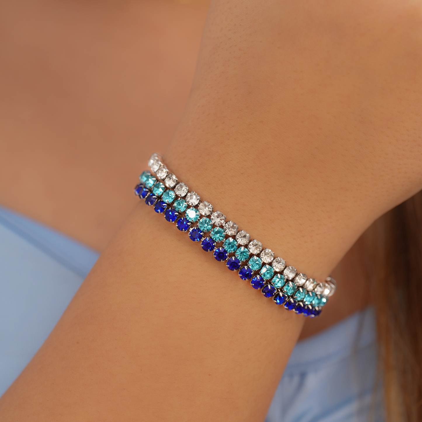 Close-up of a person's wrist wearing a bracelet with blue and silver stones, brand 'Kalopsisia' visible.