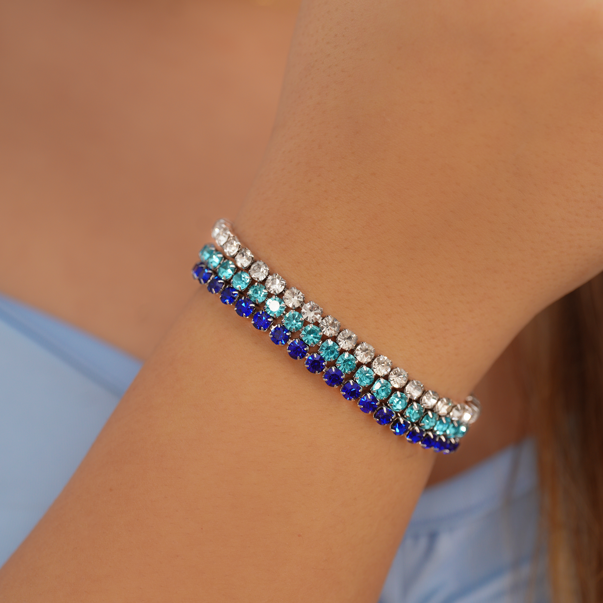 Close-up of a person's wrist wearing a bracelet with blue and silver stones, brand 'Kalopsisia' visible.
