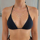 A close-up of a model wearing a gold chain body chain with coin details over a black halter bikini top.