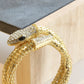 Gold snake-shaped ring on a light wooden surface