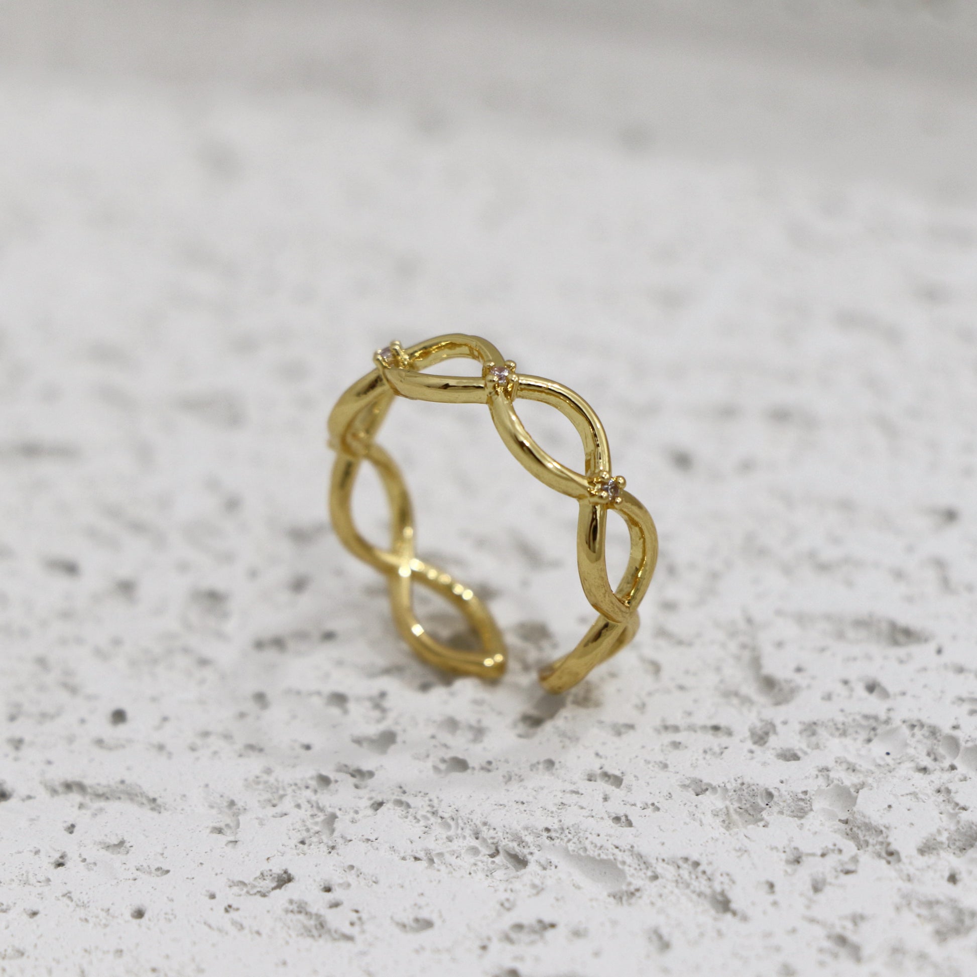 Gold ring with a textured design on a light gray surface