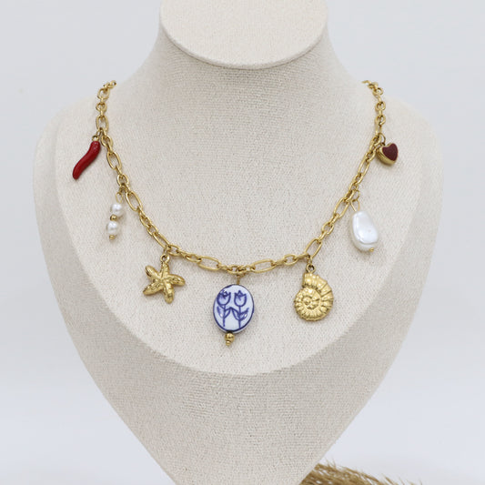Gold necklace with various charms on a mannequin bust against a white background