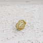 Gold ring with intricate design on a textured white surface