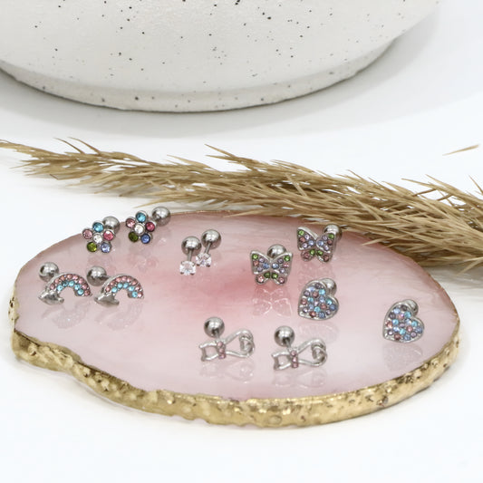 Set of small jewelry items on a pink stone with a white background