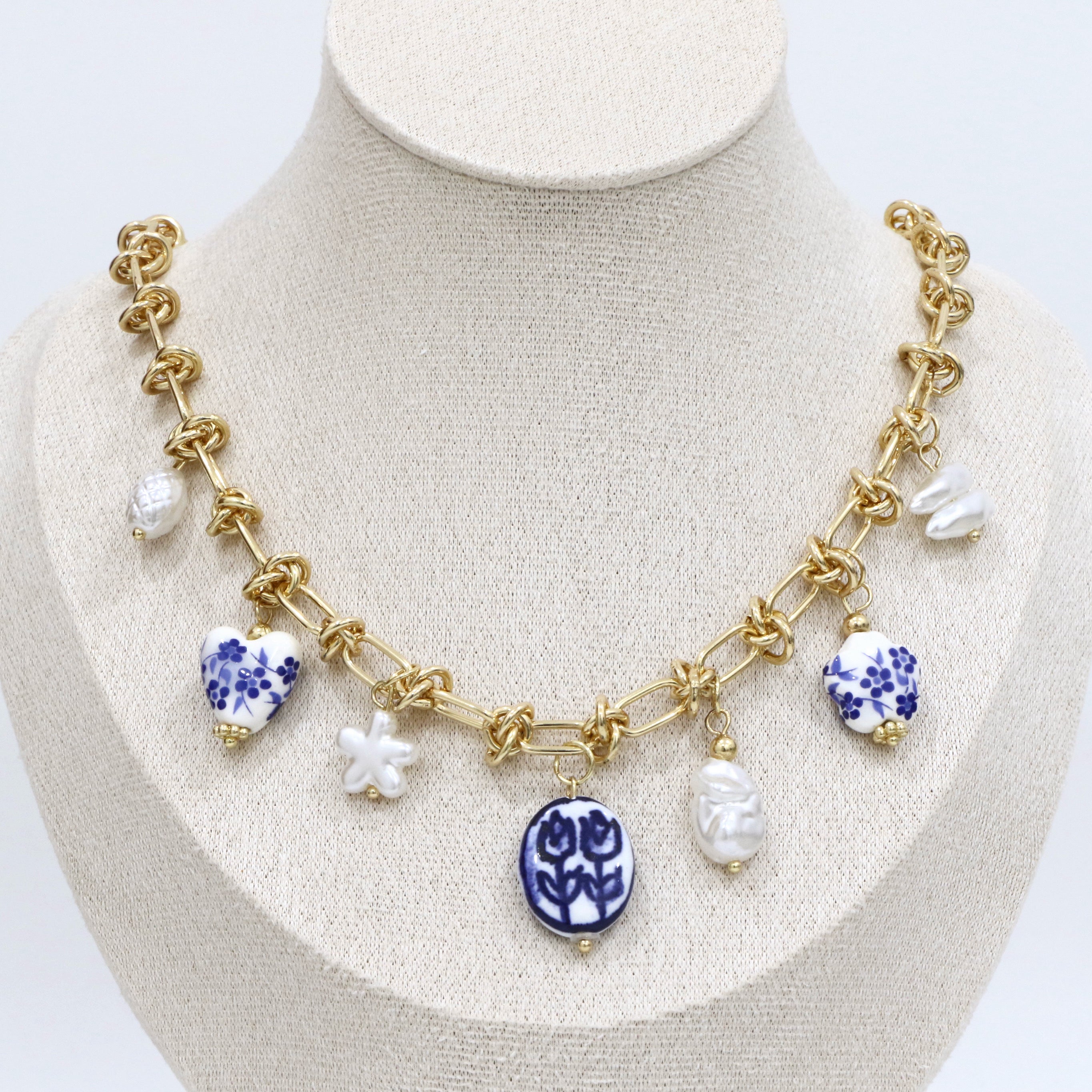 Necklace with gold chain and ceramic beads on a mannequin bust.