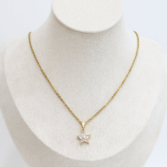 Gold necklace with a star-shaped pendant on a mannequin bust.